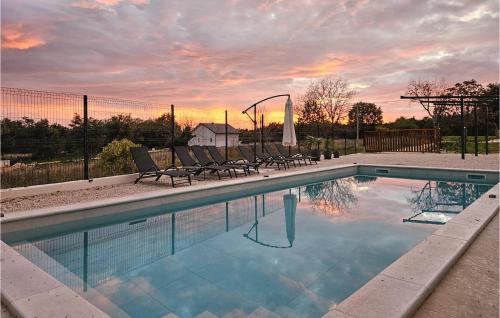 una piscina con sedie e un tramonto sullo sfondo di Cozy Home In Zminj a Jurići