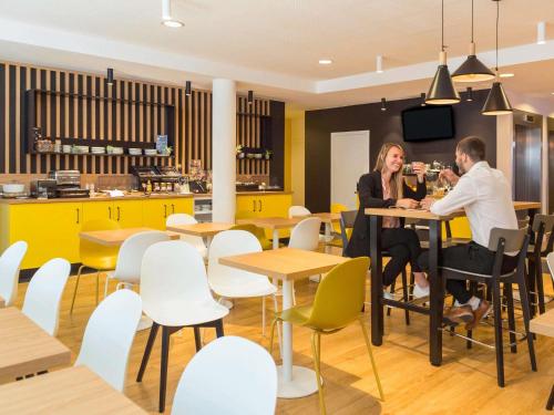 two people sitting at a table in a restaurant at Aparthotel Adagio Access Bruxelles Europe Aparthotel in Brussels
