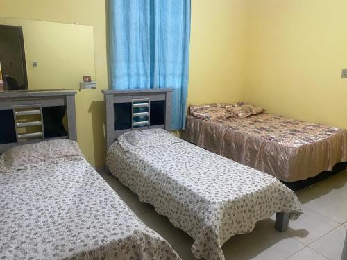 a bedroom with two beds and a mirror at PENSÃO da DONA FATIMA in Conceição do Mato Dentro