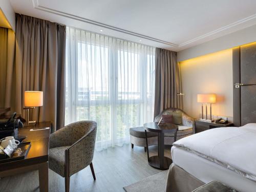 a hotel room with a bed and a desk and a room at Pullman Munich in Munich