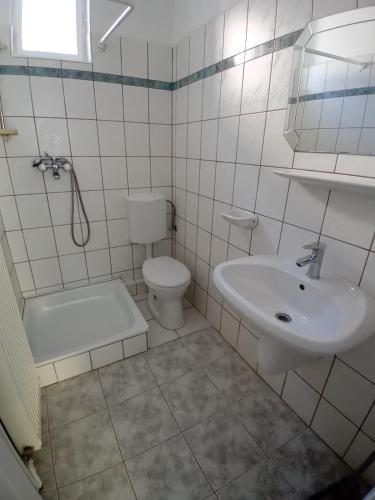 a white bathroom with a sink and a toilet at Bükfürdő Bercsényi 13 apartmanház, Bükfalva in Bük