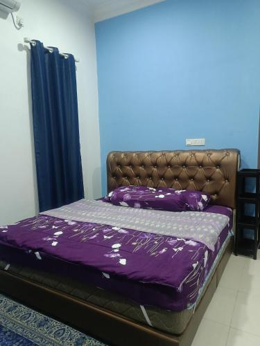 a bed in a room with a purple comforter at Sweethome MAMA in Kuala Terengganu
