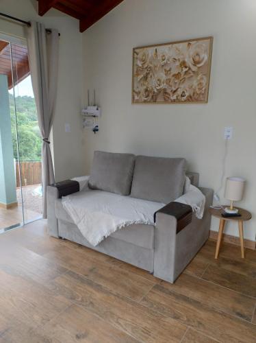 a couch sitting in a living room with a table at Cabana Sol Poente PR in São José dos Pinhais