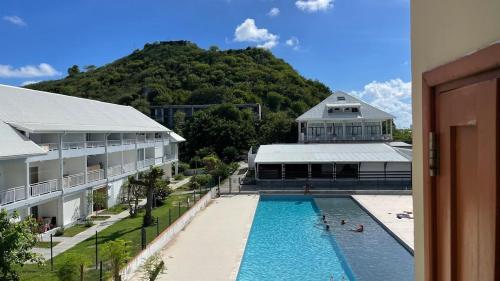 a swimming pool in front of a building with a mountain at Beachfront Studio in Marigot