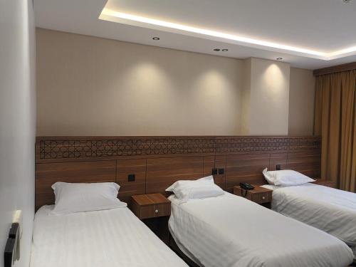 a hotel room with two beds with white sheets at فندق مكين in Al Madinah