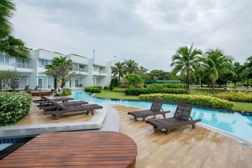 un complexe avec une piscine, des bancs et des palmiers dans l'établissement Boathouse Hua Hin Condo, à Ban Bo Fai (1)