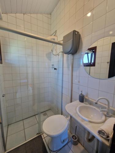 a bathroom with a toilet and a sink and a mirror at Pousada Aconchego do Rosa - Centrinho do Rosa in Praia do Rosa