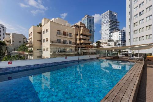 a large swimming pool in a city with tall buildings at Metropolitan Hotel in Tel Aviv