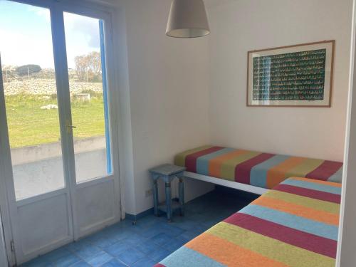 een kamer met 2 bedden en een raam met een deur bij La Villa di Nina in Favignana