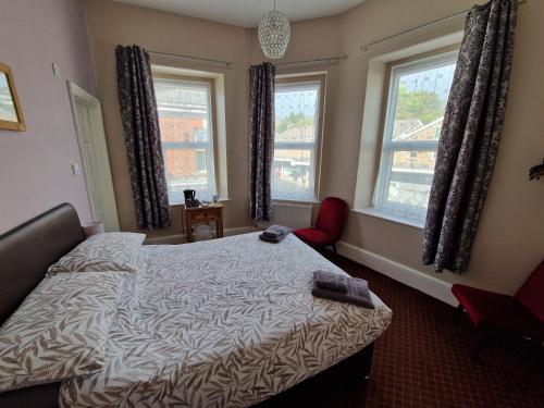 a bedroom with a bed and two windows at The Swan Hotel in Lydney