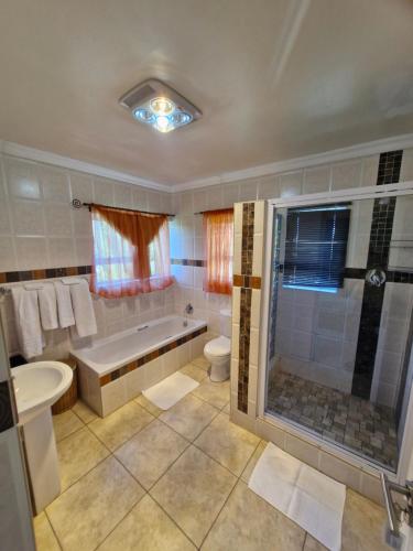 a bathroom with a tub and a toilet and a sink at Lumley's Place Guesthouse in Pniel
