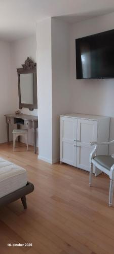 a white living room with a tv and a desk at Apartments CLIFF Piran in Piran