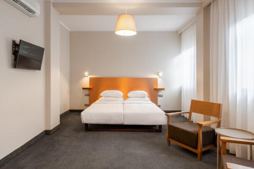 a bedroom with a white bed and a chair at RIJA Riga City Centre Hotel in Riga