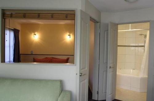 a bathroom with a mirror and a tub and a bedroom at Athena Motel in Christchurch