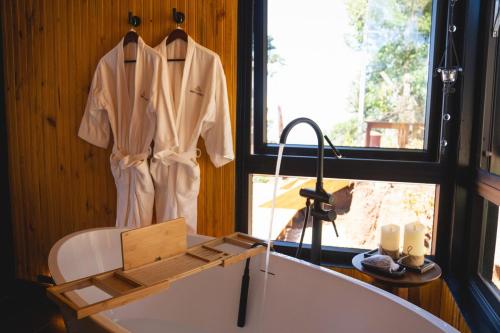 a bathroom with a bath tub and a robe hanging on a window at Luxury Cabin at 1,600m altitude in São Bento do Sapucaí