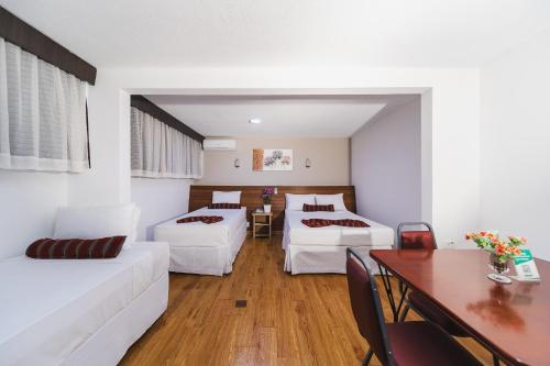 a living room with two beds and a table at Hotel Nacional Inn Curitiba Estação Shopping in Curitiba