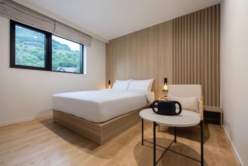 a bedroom with a bed and a table and a chair at 호텔 리브몬트 단양 by 아늑 