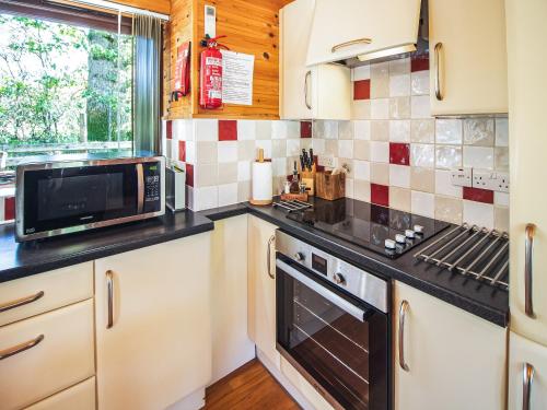 Una cocina con gabinetes blancos y un horno de estufa. en Ash Lodge - Hw7442, en Nantmel