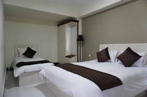 a bedroom with two beds with white sheets and brown pillows at Herat Star Hotel in Herāt