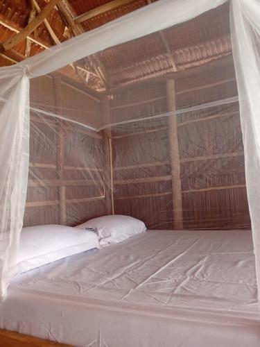 a bed in a room with a mosquito net at Naviza Homestay in Kepulauan Fam