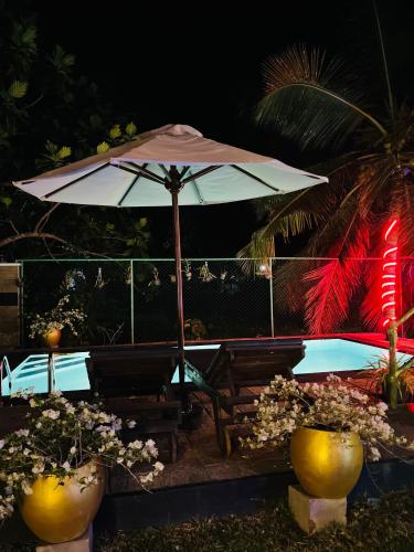 an umbrella sitting next to a bench and a pool at Shells Villa Hikkaduwa in Hikkaduwa