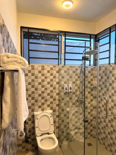a bathroom with a toilet and a glass shower at Marafiki Villa in Dar es Salaam