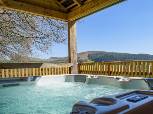 a hot tub on a deck with a wooden fence at Red Kite Lodge - Uk32610 in Old Radnor