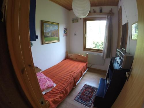 a small bedroom with a bed with an orange sheet at A nice view, panorama over Lago Maggiore in Ronco sopra Ascona