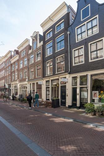 two people walking down a street in front of buildings at Herenstraat Residence in Amsterdam