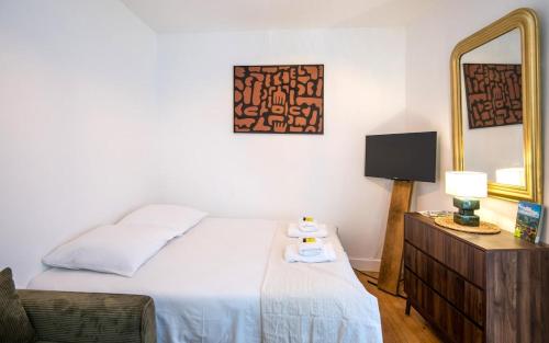 a bedroom with a bed and a mirror and a chair at le cocon du beffroi centre ville in Millau