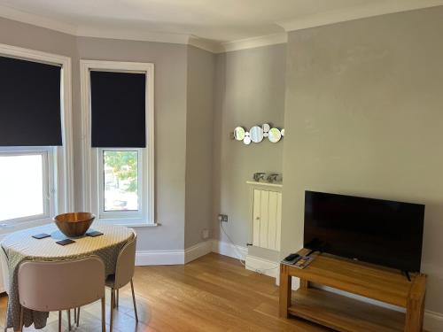a living room with a flat screen tv and a table at Sandown Seaside apartment First Floor Kasala in Sandown