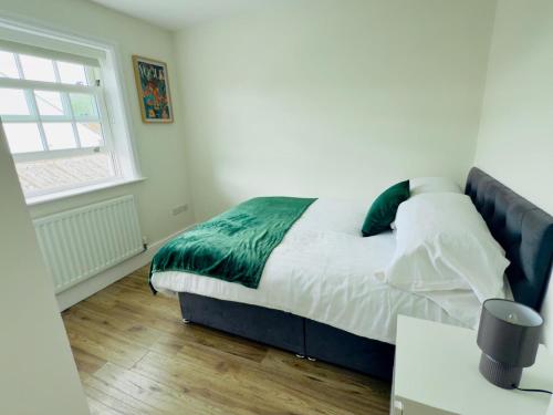 a bedroom with a bed with a green blanket and a window at Union Apartment - Light and Airy in Bedford