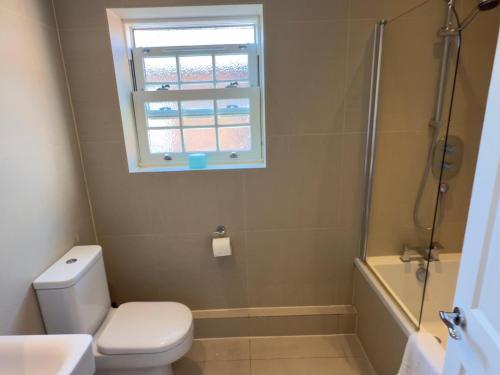 a bathroom with a toilet and a window and a shower at Union Apartment - Light and Airy in Bedford