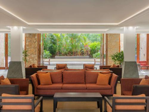 a lobby with a couch and tables and a large window at Pullman Palm Cove Sea Temple Resort & Spa in Palm Cove