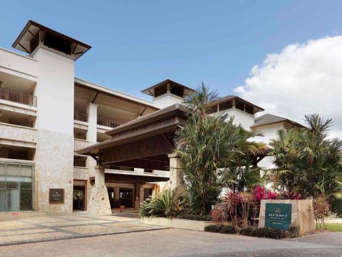 a building with palm trees in front of it at Pullman Palm Cove Sea Temple Resort & Spa in Palm Cove