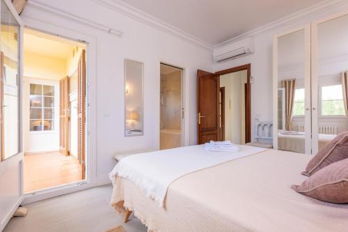 a white bedroom with a large bed and windows at Casa Leo in Playa de Muro
