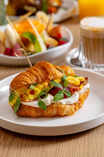 ein Sandwich auf einem weißen Teller auf einem Tisch in der Unterkunft The Rome EDITION in Rom