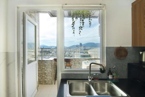 a kitchen with a sink and a large window at Sóng Apartment - Seaside retreat in Da Nang