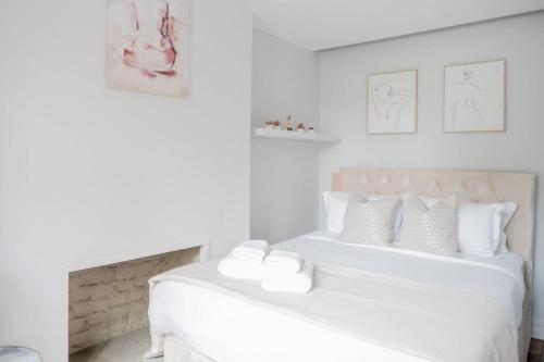 a white bedroom with two beds with white pillows at Stylish Flat in the heart of South Kensington in London