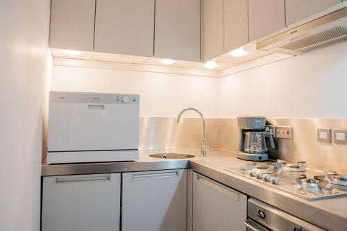 a kitchen with white cabinets and a sink and a stove at Stylish Flat in the heart of South Kensington in London