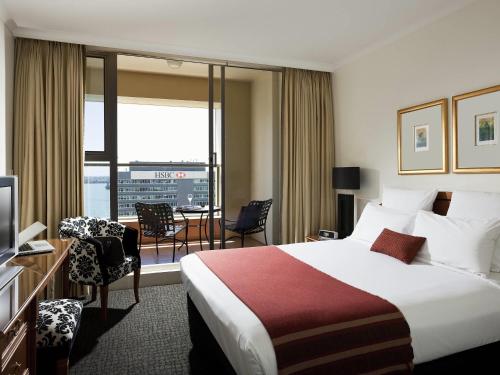 Una habitación de hotel con una cama, un escritorio y una ventana. en The Sebel Quay West Auckland, en Auckland