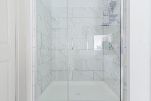a white bathroom with a shower with a glass door at Blueground Del Valle pool nr McKinney Falls ATX-354 in Austin