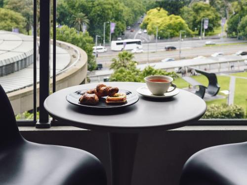 a table with a plate of donuts and a cup of coffee at Quay West Suites Melbourne in Melbourne