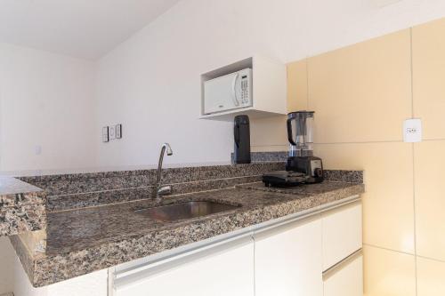a kitchen with a sink and a microwave at Beach Townhouses - Porto das Dunas By Carpediem in Mangabeira