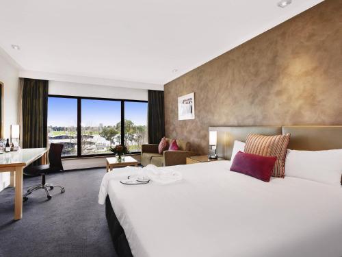 a hotel room with a large bed and a desk at Mercure Melbourne Albert Park in Melbourne