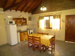 une cuisine avec une table avec des chaises et un réfrigérateur dans l'établissement Antawara, à Merlo