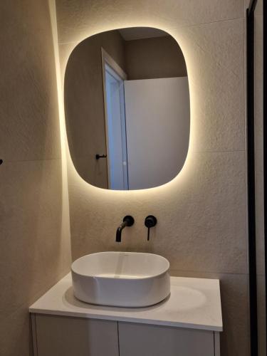 een badkamer met een witte wastafel en een spiegel bij Hypnos Residence Acropolis in Strovolos