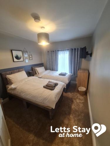 a hotel room with two beds and a window at Coachway Cottage in Ilkley