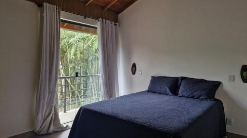 une chambre avec un lit bleu et une fenêtre dans l'établissement Casa shizen, à Nova Friburgo