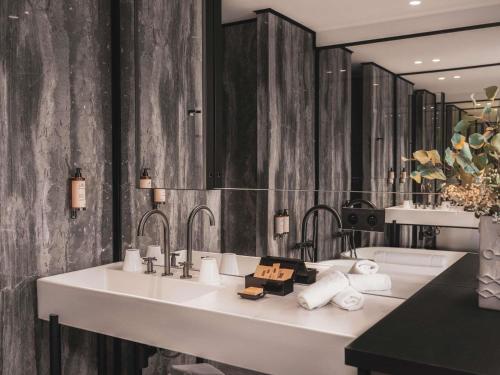a bathroom with a sink and a large mirror at Balthazar Hotel & Spa Rennes - MGallery Collection in Rennes